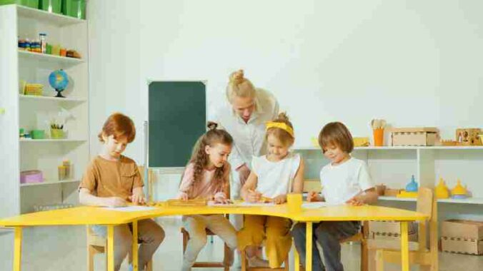 A teacher guides young students in a bright classroom setting., tags: england und wales - pexel